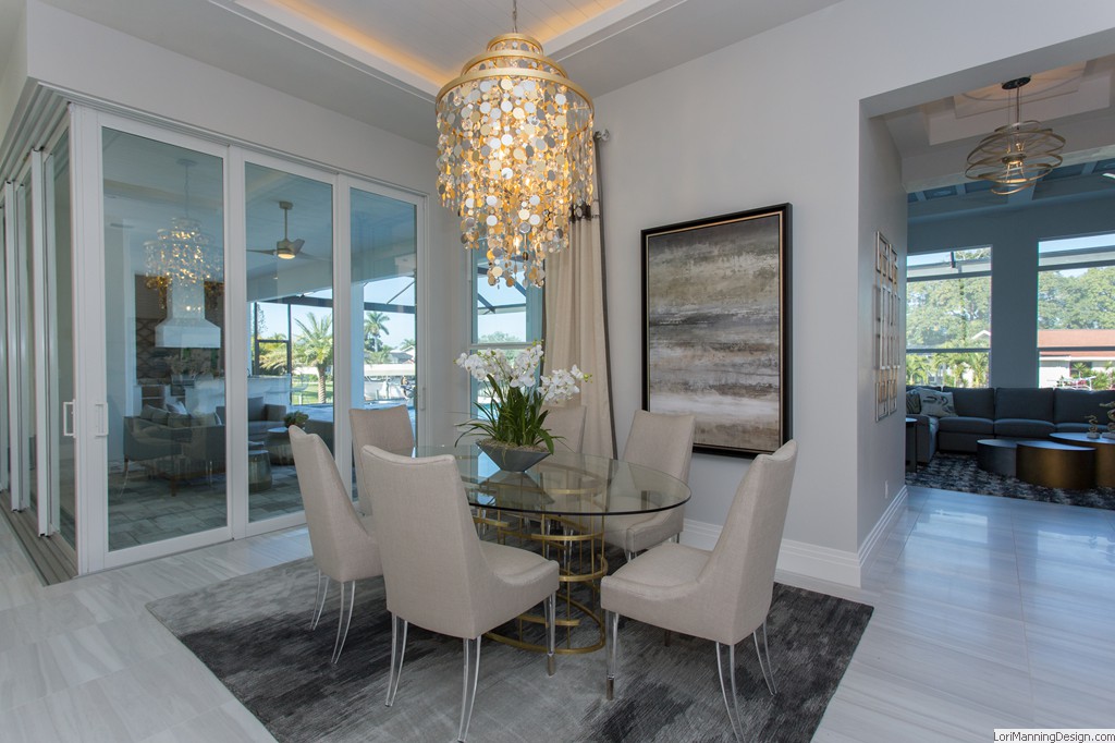 Dining Room features glass table with gold base, silk chairs with acrylic legs, acrylic furniture